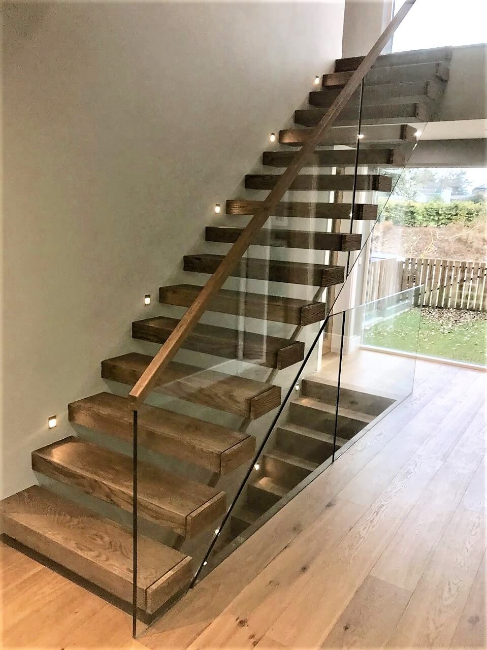 Dark oak floating stairs with glass balustrade and LED lighting
